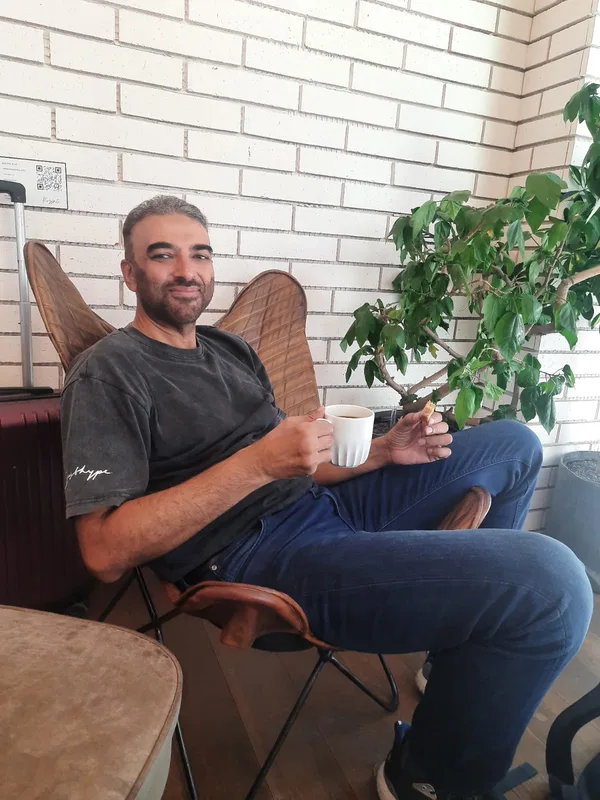 Aamir Malik, seated with a cup of coffee.